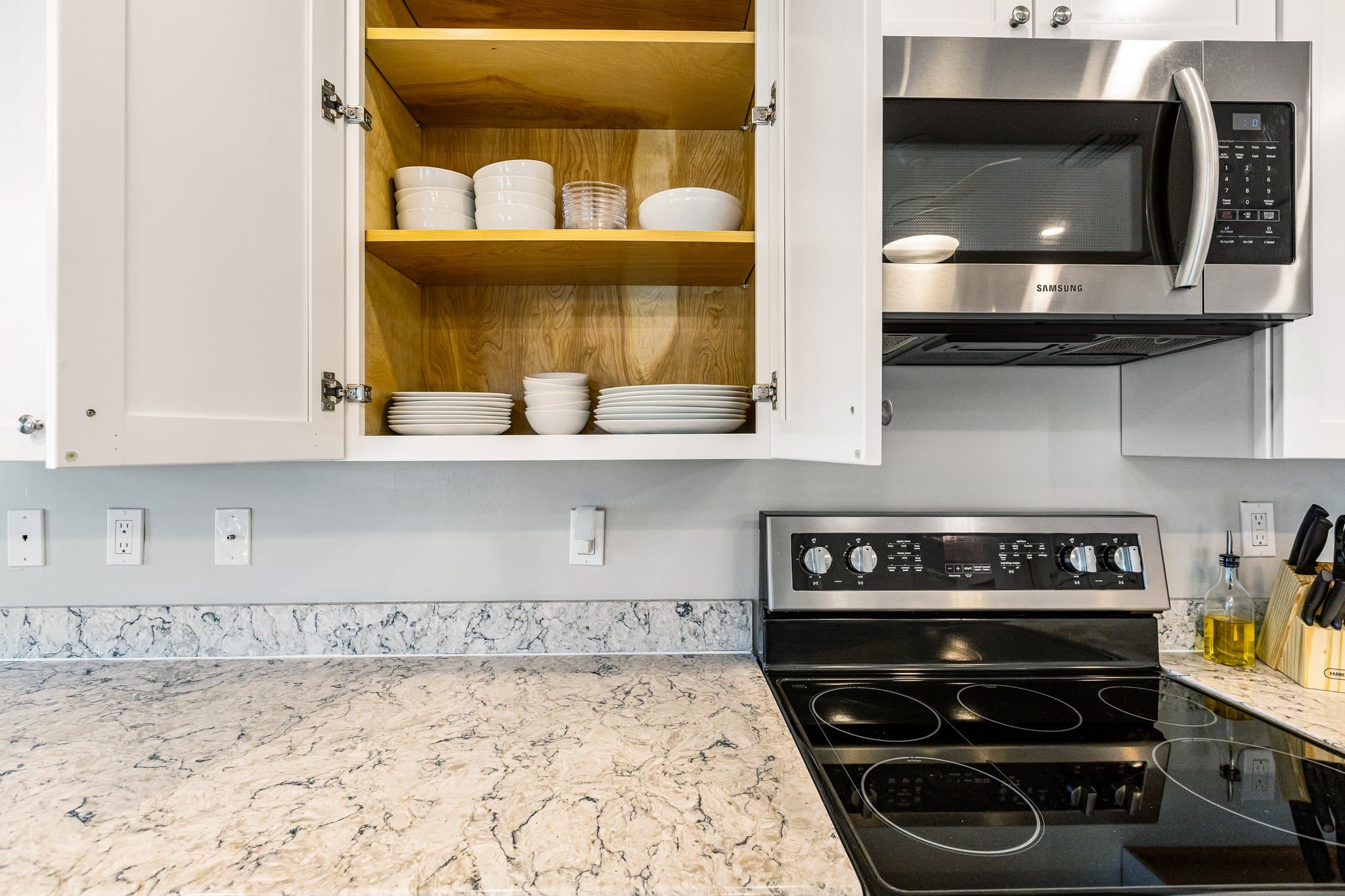 Kitchen cabinets stocked with dishes beside the range