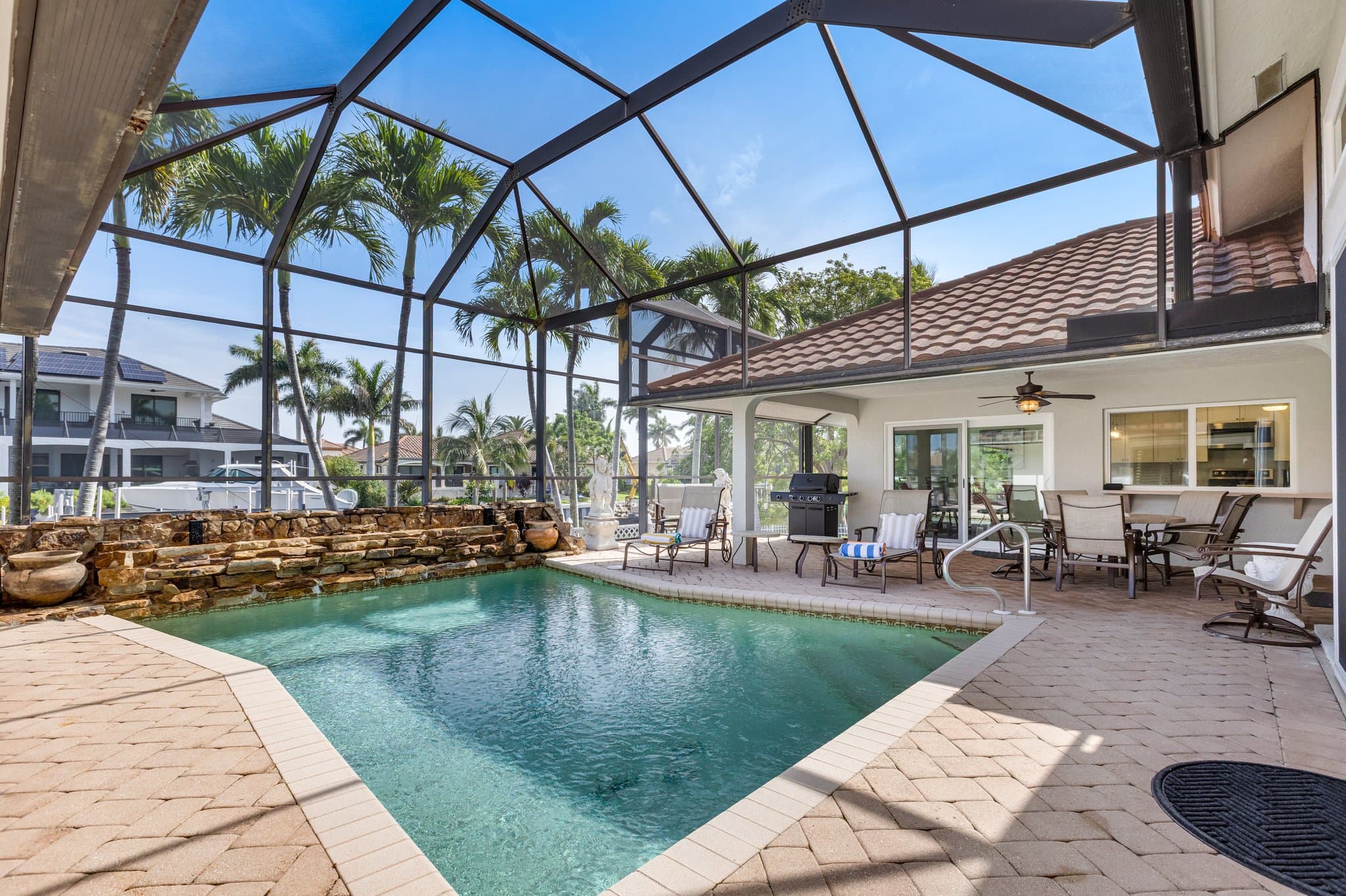 Screened pool cage with rock waterfall feature and covered lanai