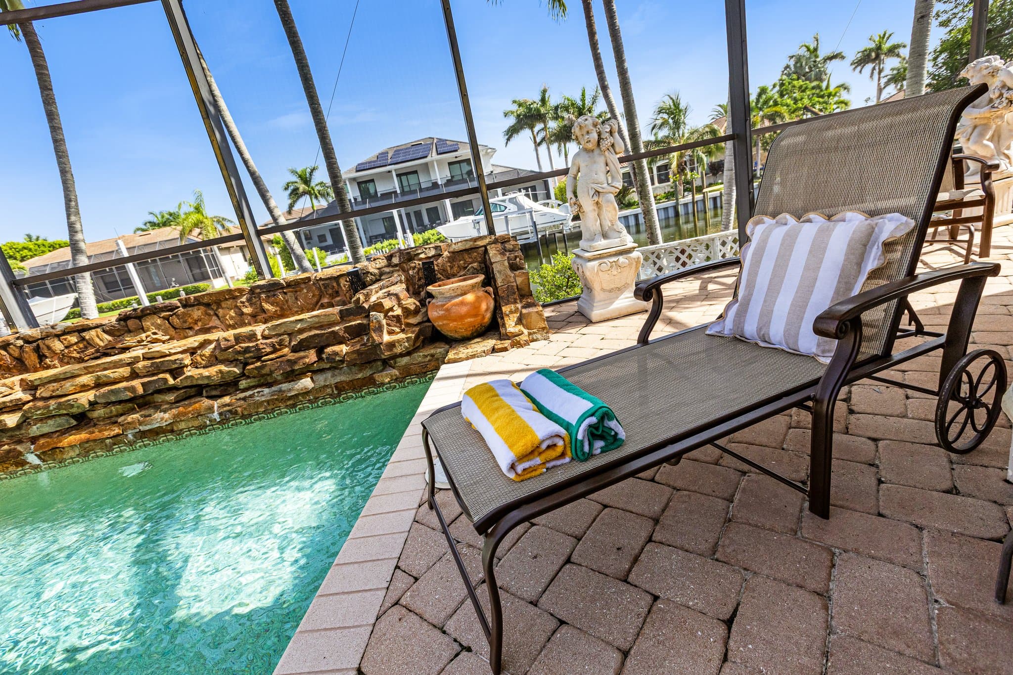 Poolside lounge chair with beach towels and canal view