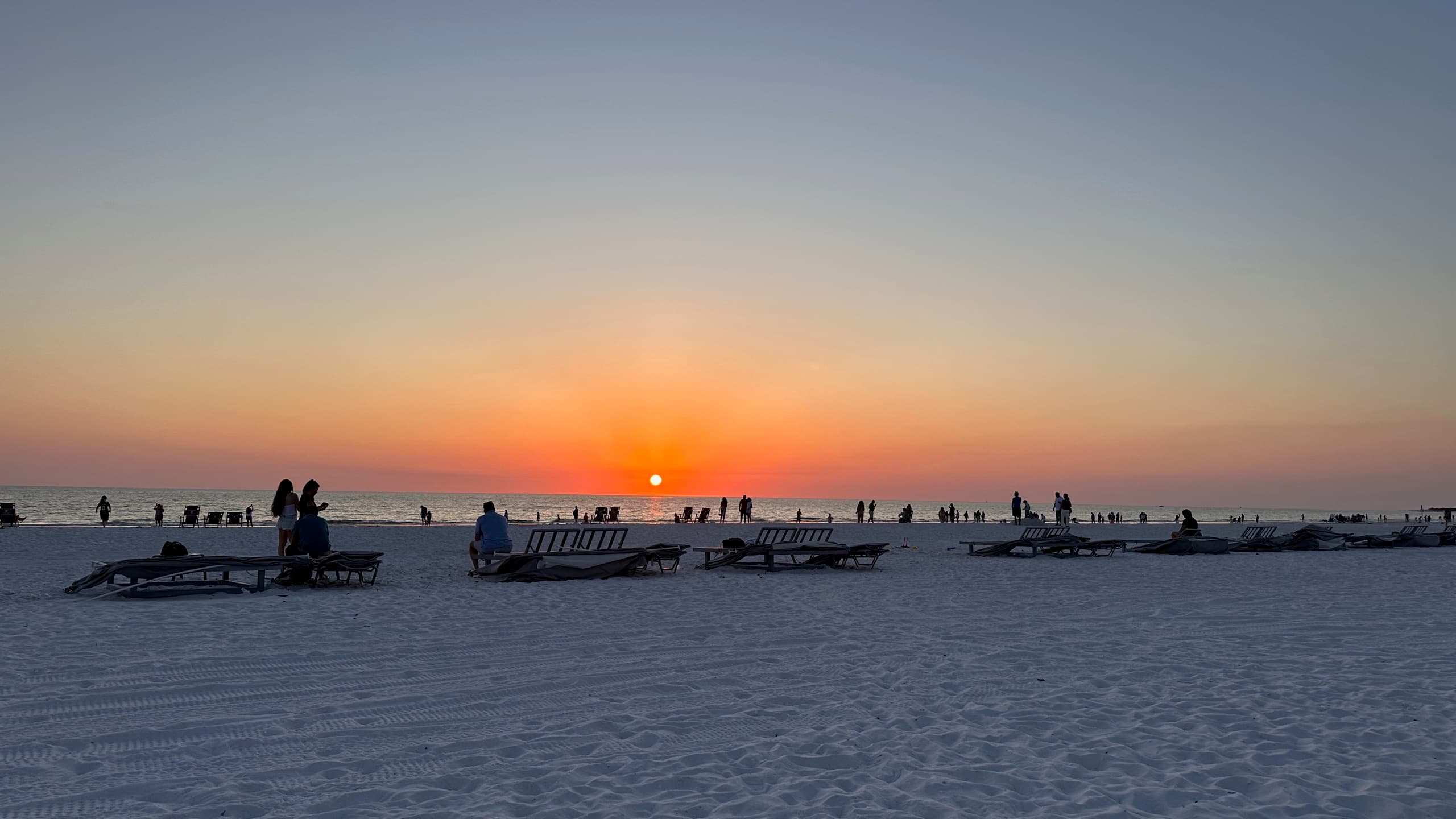 Sunset over the Gulf from the beach, loungers out on the white sand