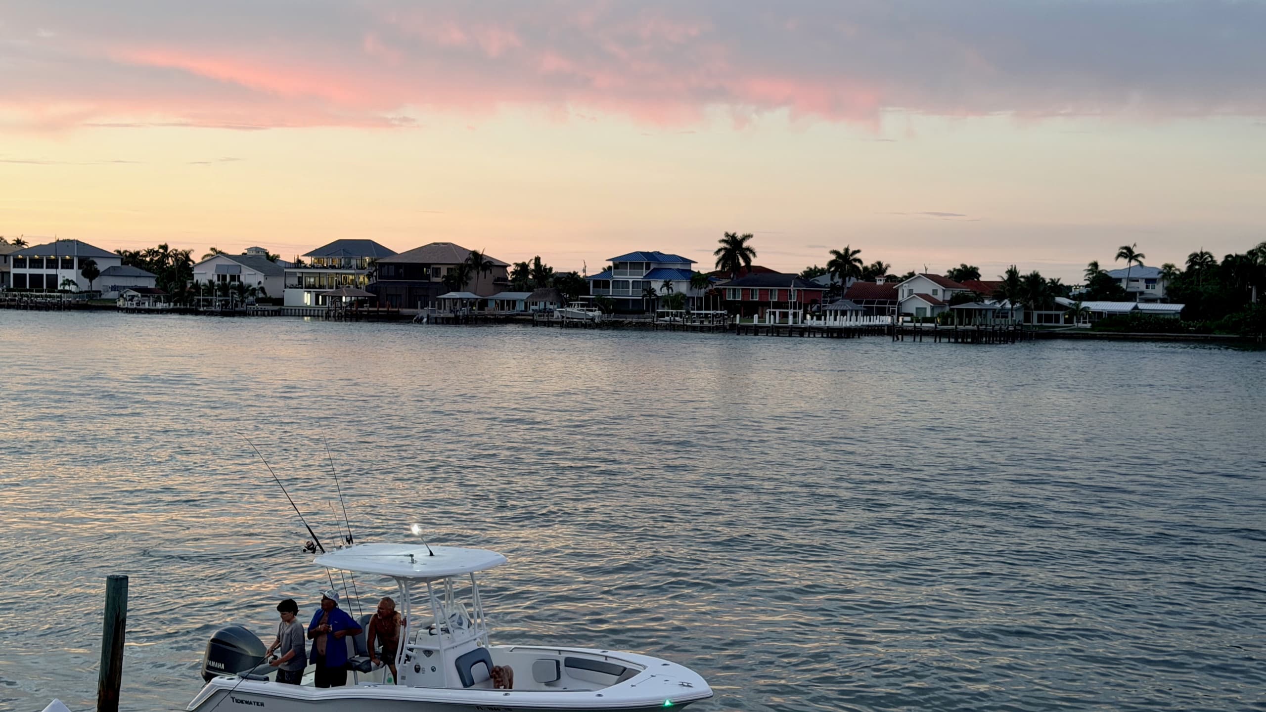 Sunset over the bay, a fishing boat heading in past waterfront homes
